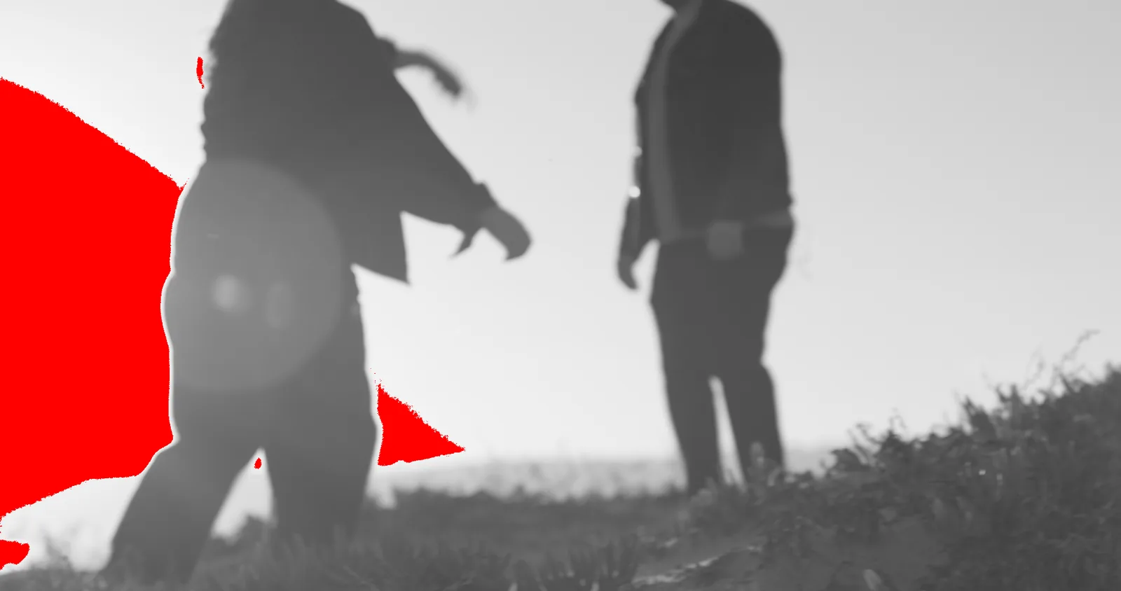 Two figures walking into a low sun, the clipped flare painted red.